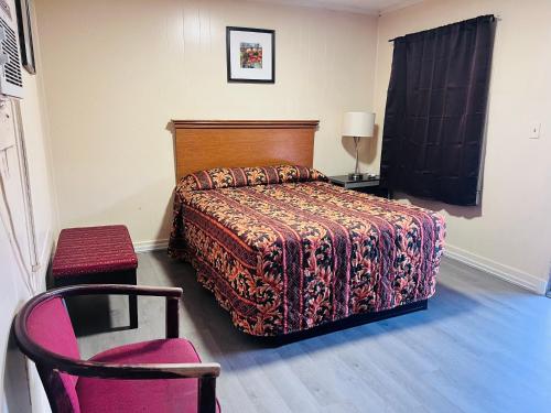 ein Schlafzimmer mit einem Bett und einem rosa Stuhl in der Unterkunft Budget Motel in Manning