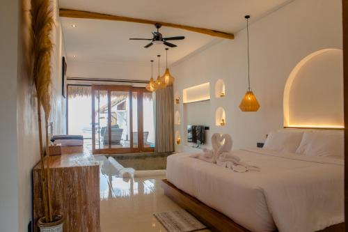 a bedroom with a large white bed and a living room at Miwa Bali Villa in Nusa Penida