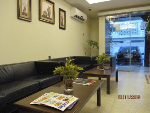 a living room with a black leather couch and tables at Sovereign Hotel - Marriage Certificate Required in Doha
