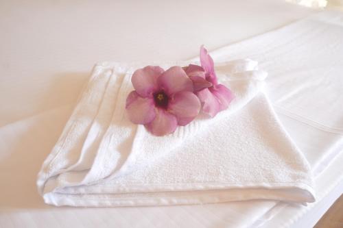 eine rosa Blume auf einem weißen Handtuch in der Unterkunft Sanmi Runway View Resort in Kimbulapitiya