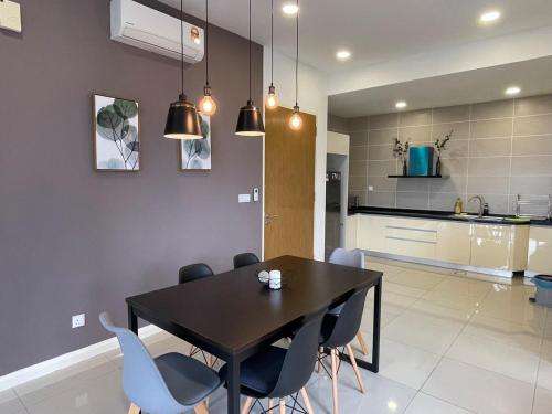 a kitchen and dining room with a black table and chairs at D Pristine 3 bedroom residence next to legoland in Iskandar Puteri