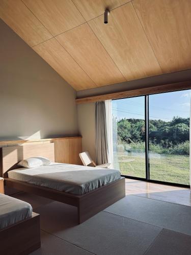 a bedroom with two beds and a large window at 2R Yakushima in Yakushima