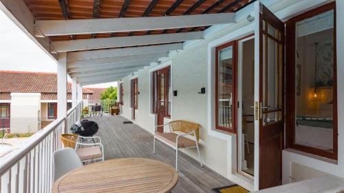 Un porche con una mesa y sillas de madera en una casa. en Dune Sanctuary, en Plettenberg Bay