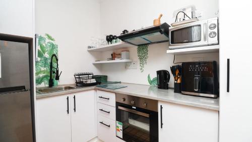 Una cocina con gabinetes blancos y un microondas. en Dune Sanctuary, en Plettenberg Bay