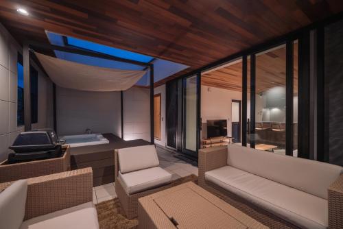 a room with a couch and chairs and a tub at Sanctuary Villa & Sauna Ogimi by Relapool in Banchi