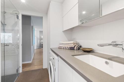 a white kitchen with a sink and a shower at Salt and Sea on Marine in Kingscliff