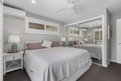 a bedroom with a large white bed and a mirror at Salt and Sea on Marine in Kingscliff