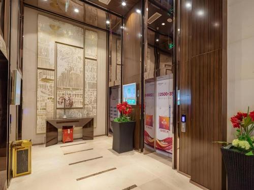a lobby of a building with a desk and flowers at VX Hotel Wuxi Xinwu District Executive Center Wanda Plaza in Wuxi