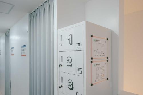 a white locker with numbers on it in a room at トランジットホステル Transit Hostel in Izumi-Sano