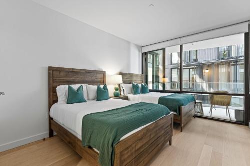 a bedroom with two beds and a large window at Pearl Coast - Modern 2BR with Rooftop Pool & Views in Los Angeles