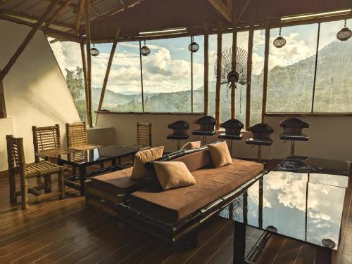 a living room with a couch and a table and windows at Dzukou Lodge in Kohīma
