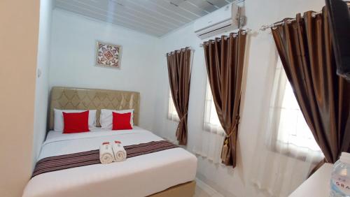 a bedroom with a bed with red pillows and a window at House of A Syariah Kedamaian in Bandar Lampung