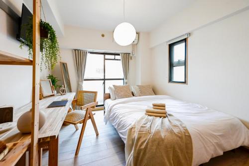 a bedroom with a large bed with a desk and a desk at Japandi 6 Inspired 1BR in Prime City Spot and Near Station in Fukuoka