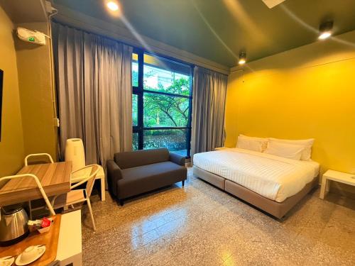 a bedroom with a bed and a chair and a yellow wall at Work Den Chiangrai in Chiang Rai