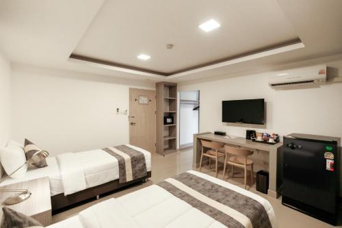 バンコクにあるUTD8 Hotel and Residenceのベッド2台と机があるホテルの部屋
