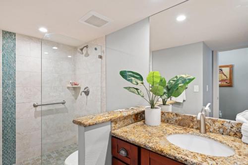 Un baño con lavabo y ducha de cristal. en Lahaina Shores 234, en Wainee