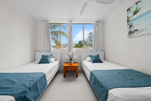 two beds in a room with a window at Sandcastles On Currumbin Beachfront, Gold Coast in Gold Coast