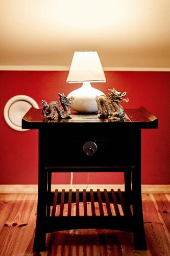 a table with a lamp on a red wall at Pałac Bażantarnia in Pszczyna