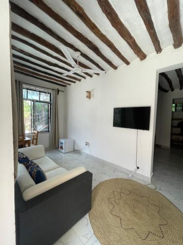 a living room with a couch and a flat screen tv at Zanzibar beach escape 1&2 in Bwejuu