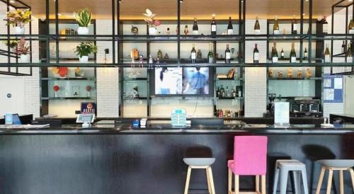 un bar dans un restaurant avec des tabourets roses et violets dans l'établissement Campanile Hotel Shenzhen Bay Convention and Exhibition Center, à Fenghuangwei