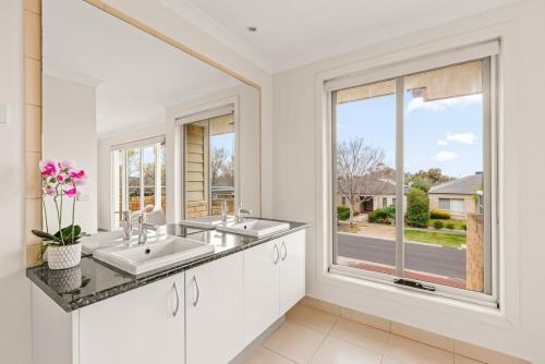 a white bathroom with two sinks and a window at StayAU Modern Sanctuary Mins from the Ct & Airport in Point Cook