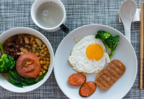 ein weißer Teller mit einem Ei und einer Schüssel Essen in der Unterkunft Wuxin Lake View Hostel in Dali