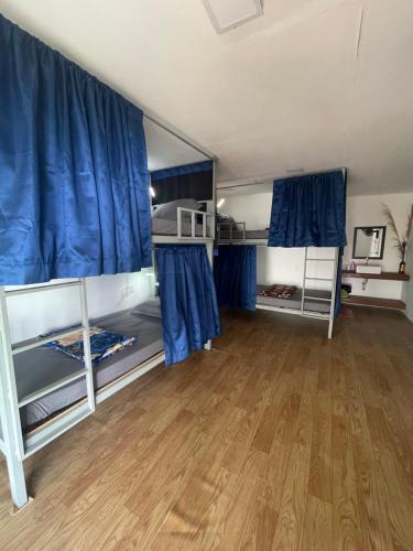 a large room with blue curtains and wooden floors at Skybar Koh Rong in Koh Rong