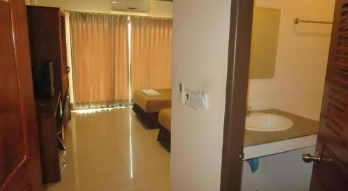 a room with a bathroom with a sink and a bed at Chaleunehoung Hotel in Ban Houadông