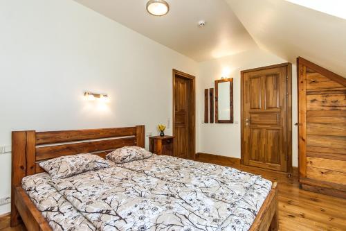 a bedroom with a large bed with a wooden headboard at Lauču Akmens in Skulte