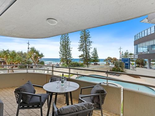 a patio with a table and chairs and a pool at Beachfront Escape Zenith - Ocean Views, Pool, Spa in Gold Coast