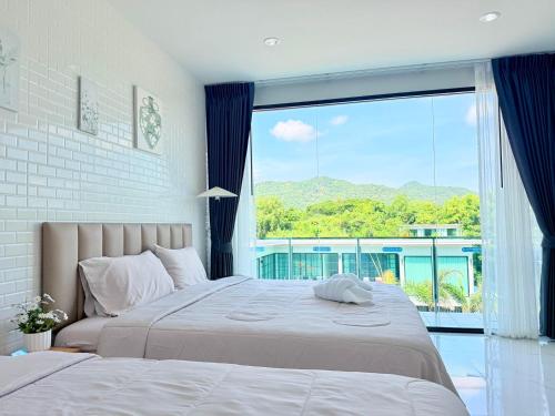 a bedroom with a large bed with a large window at The Ocean Pool Villa HuaHin in Hua Hin
