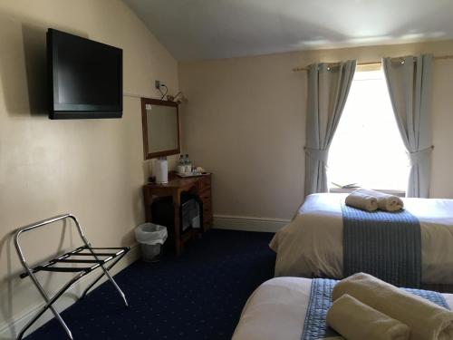 a hotel room with two beds and a flat screen tv at Cubbon House in Douglas