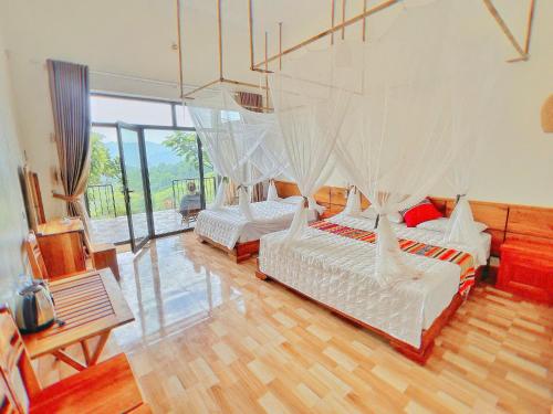 a bedroom with two beds with mosquito nets at Mai Hill Homestay in Kon Rung (1)