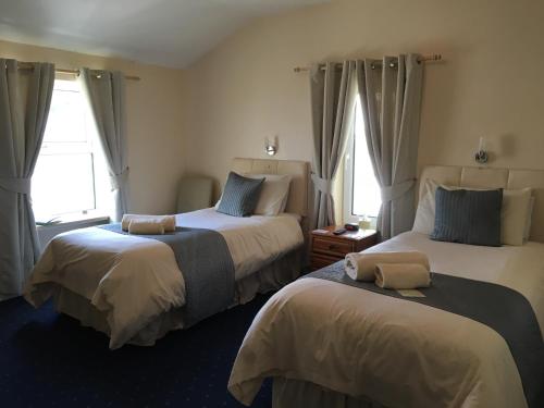 two beds in a room with two windows at Cubbon House in Douglas