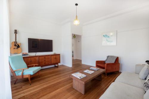 a living room with a couch and a tv at The Blue Beach House - Pet Friendly Coastal Escape in Mollymook in Mollymook