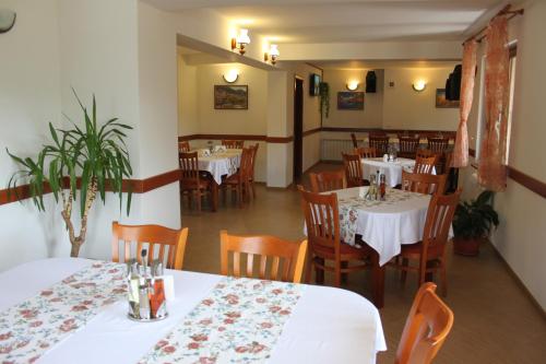 uma sala de jantar com mesas brancas e cadeiras de madeira em Kris Guest House em Devin