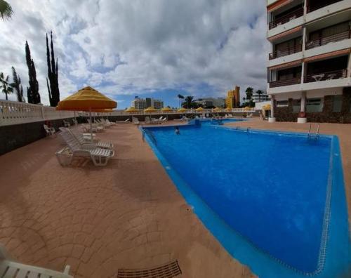 a large blue swimming pool next to a building at TENERIFE Olympia Apart Hotel-Playa de las Americas. Balcony, sea view & pool in Playa de las Americas