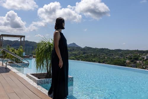 a woman in a black dress standing next to a swimming pool at El Cielo Sayulita in Sayulita