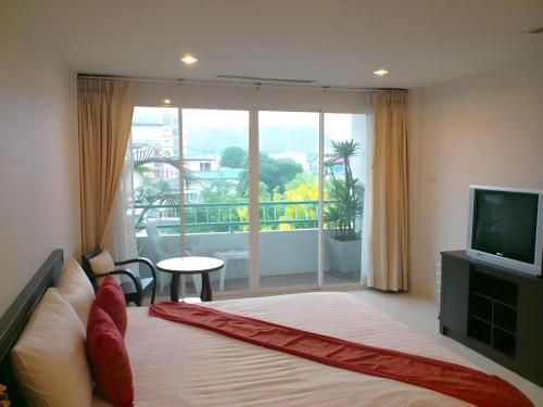 a bedroom with a bed and a television and a balcony at Hua Hin Avenue Hotel in Hua Hin