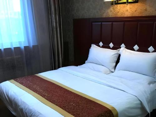 太原市にあるShell Hotel Taiyuan South Railway Station New Southeast Bus Stationの寝室にある白いシーツと枕が置かれたベッド