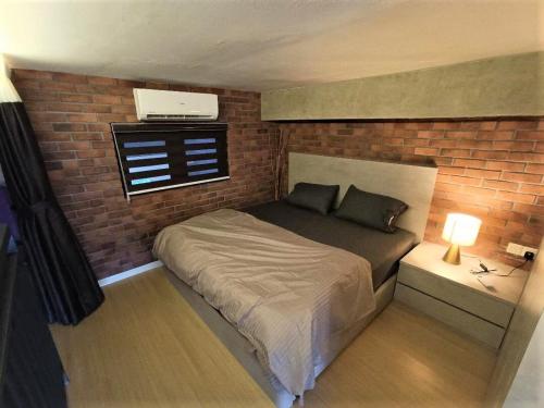 a bedroom with a bed and a brick wall at New York Style loft with computer gaming and bricks in Iskandar Puteri