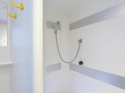 a shower with a hose attached to a wall at Lemon Hôtel Coudes in Coudes