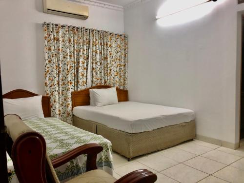 1 dormitorio con 2 camas y una ventana con cortina en Maya Eco Guest House, en Dhaka
