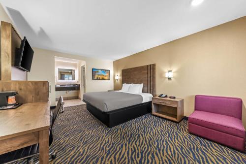 ヘスペリアにあるQuality Inn & Suitesのベッドと紫色の椅子があるホテルの部屋