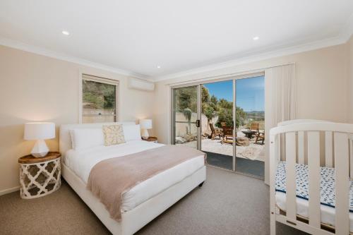 a white bedroom with a bed and a large window at Allambie - Poolside Elegance in Mudgee Countryside in Mudgee