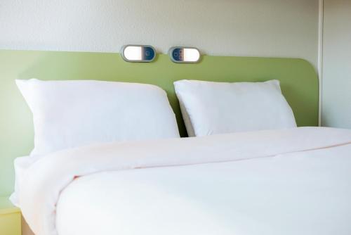 two beds in a room with two clocks on the wall at ibis Budget Courbevoie Paris La Défense in Courbevoie