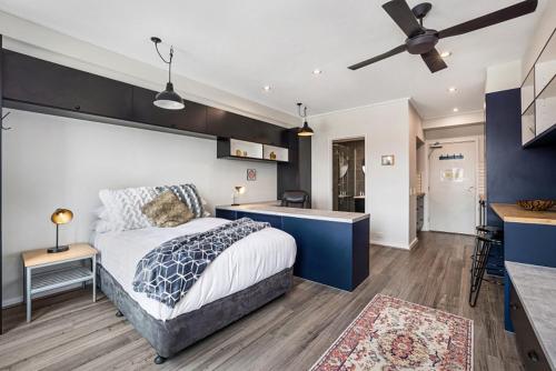 a bedroom with a bed and a kitchen with a ceiling fan at Studio Apartment near CBD, RMIT & Uni of Melbourne in Melbourne