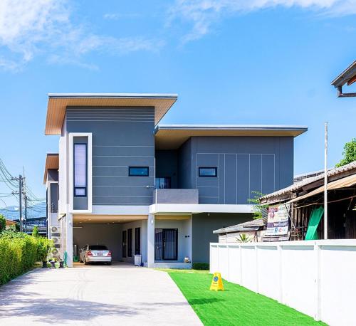 a blue house with a white fence and a driveway at Maneua Home, Mueng Chiang Mai in Chiang Mai