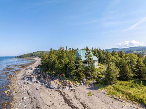 a house on a rocky beach next to the water at Spa Nature & Comfort - Chalet LRioux in Trois-Pistoles