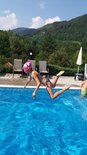 a woman jumping into a swimming pool at Hotel Perfect in Yamna